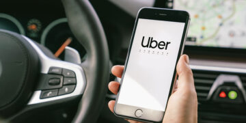 Aachen, Germany September 2019: Uber driver holding his smartphone in car. Uber is an American company offering different online transportation services