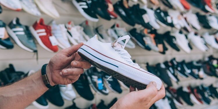 Man holds sports sneakers in his hand in a supermarket